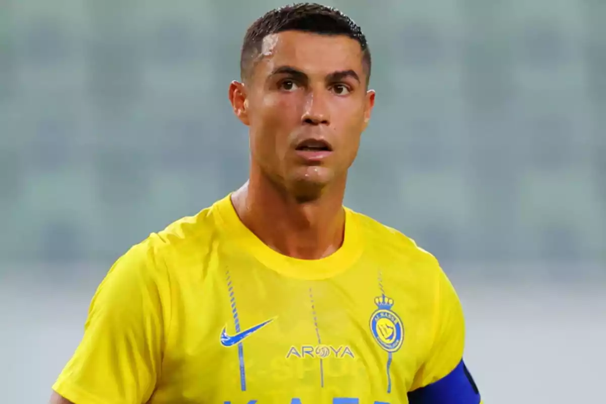 Un jugador de fútbol con camiseta amarilla y brazalete azul en el campo.