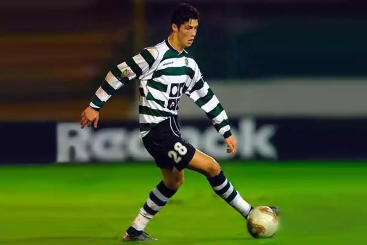 Un jugador de fútbol con uniforme a rayas verdes y blancas controla el balón en el campo.