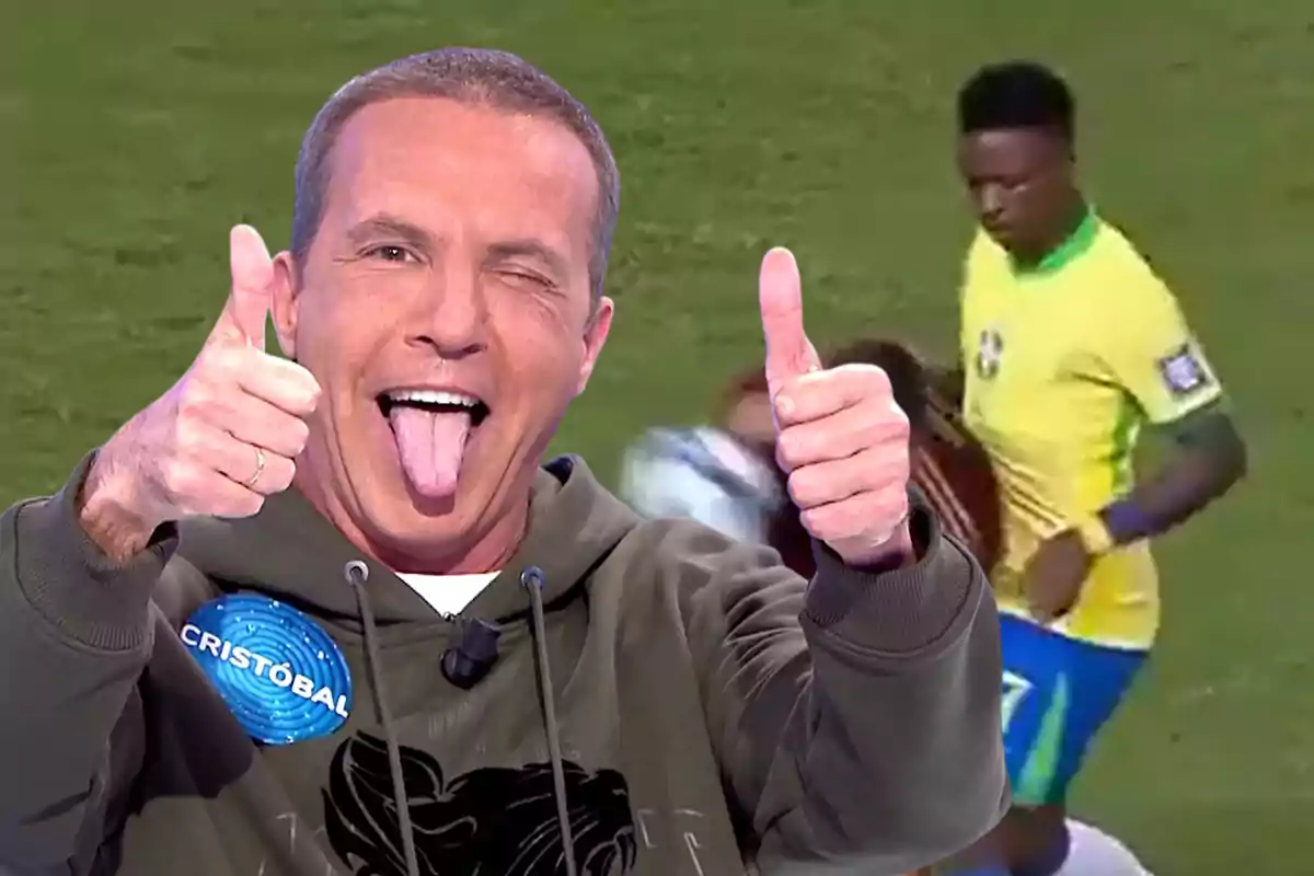 Un hombre sonriente con la lengua afuera y levantando ambos pulgares, con un fondo de un partido de fútbol.