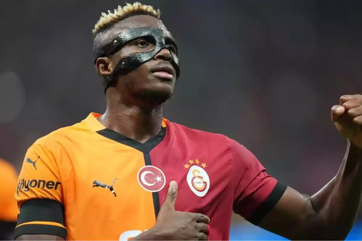 Un futbolista con máscara facial y uniforme del Galatasaray celebra con el puño levantado. Un futbolista con máscara facial y uniforme del Galatasaray celebra con el puño levantado.