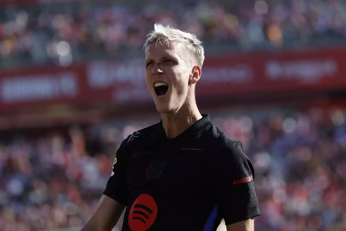 A soccer player in a black jersey celebrates in a stadium full of spectators. A soccer player in a black jersey celebrates in a stadium full of spectators.