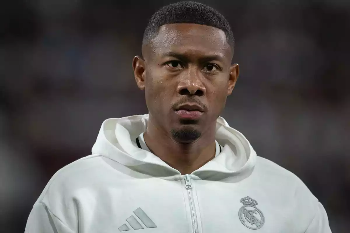 Jugador de fútbol con sudadera blanca del Real Madrid mirando al frente en un estadio