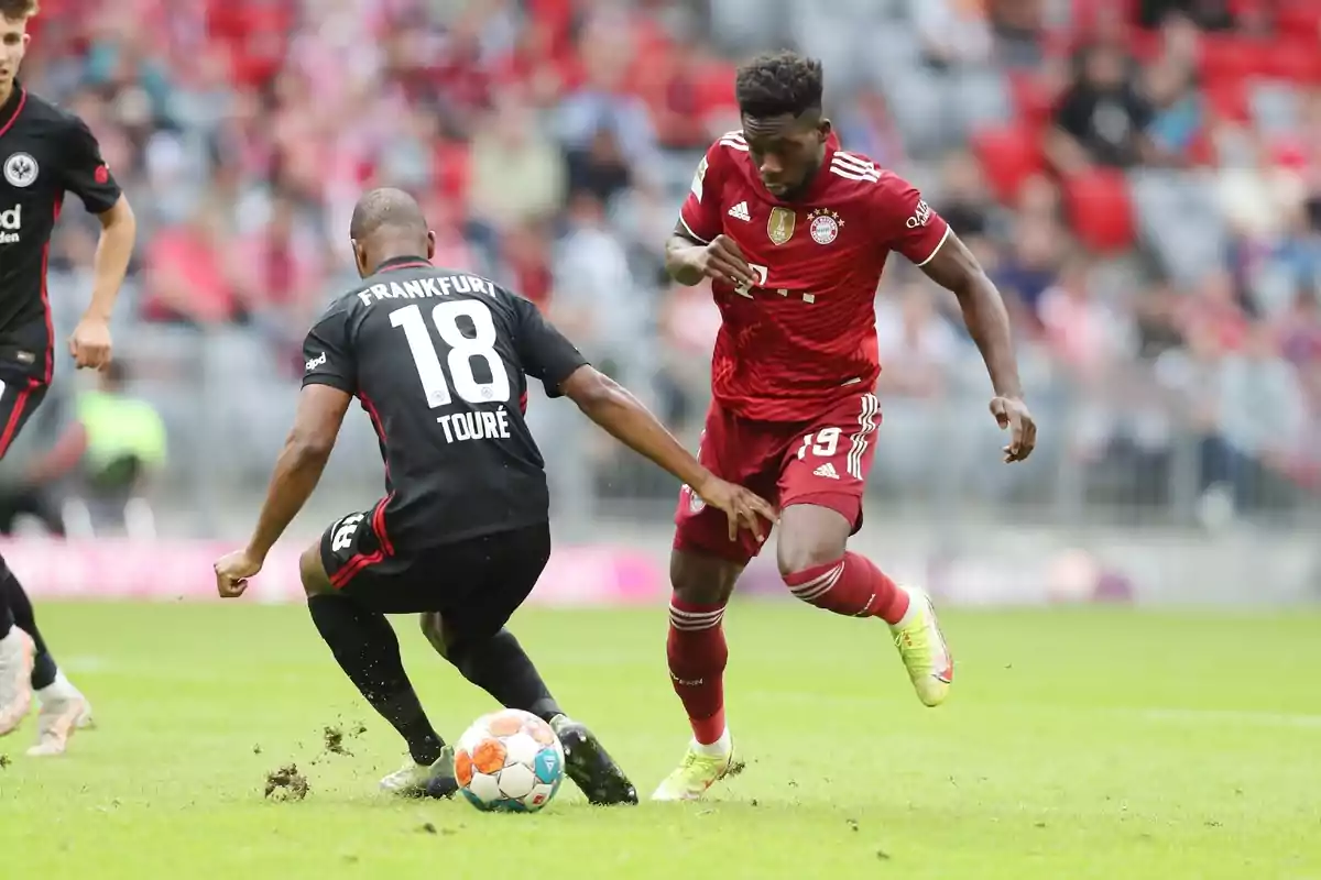 Two soccer players compete for the ball in a game, one in a red uniform and the other in a black uniform. Two soccer players compete for the ball in a game, one in a red uniform and the other in a black uniform.