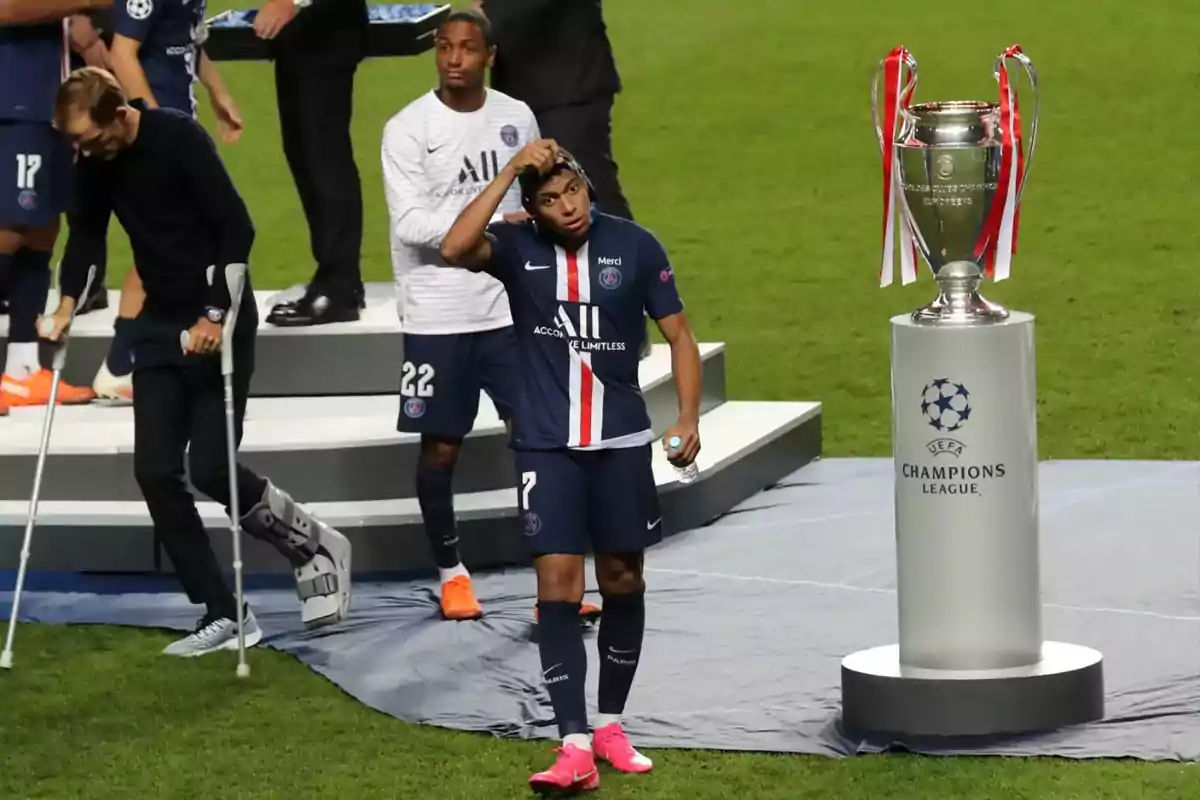 PSG players walk past the Champions League trophy with their heads down after losing the final. PSG players walk past the Champions League trophy with their heads down after losing the final.