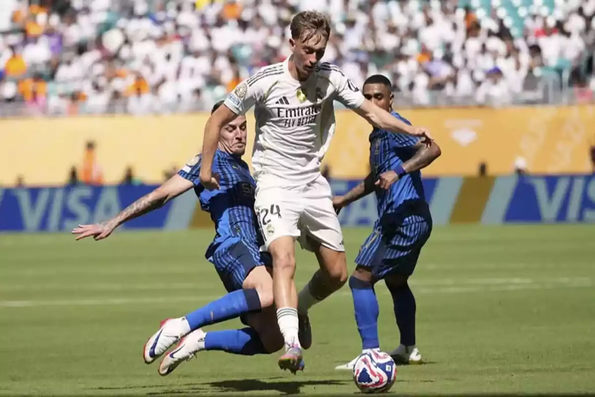Un jugador del Real Madrid intenta avanzar con el balón mientras dos rivales del Inter de Milán intentan detenerlo durante un partido de fútbol en un estadio lleno de espectadores. Un jugador del Real Madrid intenta avanzar con el balón mientras dos rivales del Inter de Milán intentan detenerlo durante un partido de fútbol en un estadio lleno de espectadores.