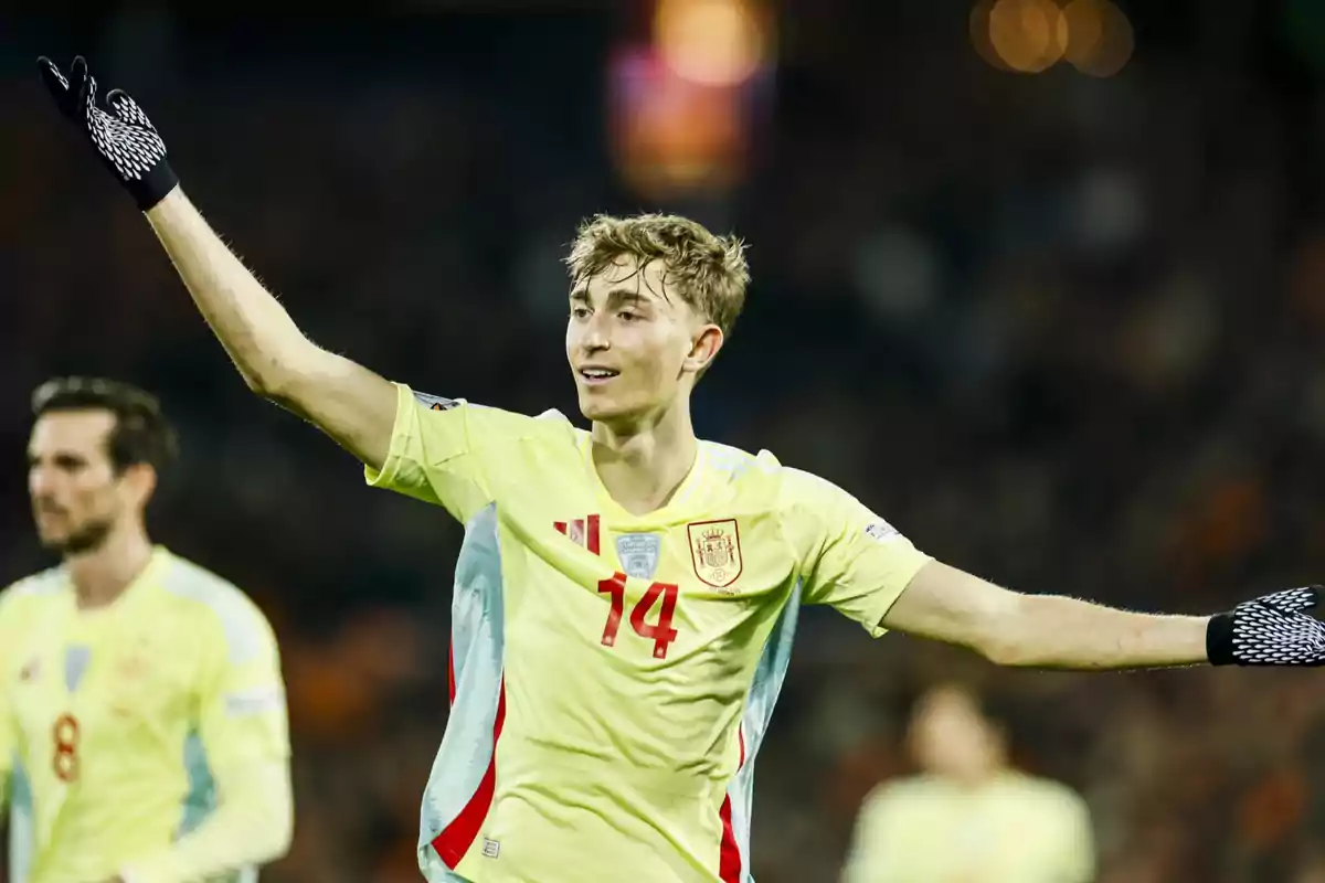 A player in the Spanish national team uniform raises his arms on the field during a match. A player in the Spanish national team uniform raises his arms on the field during a match.