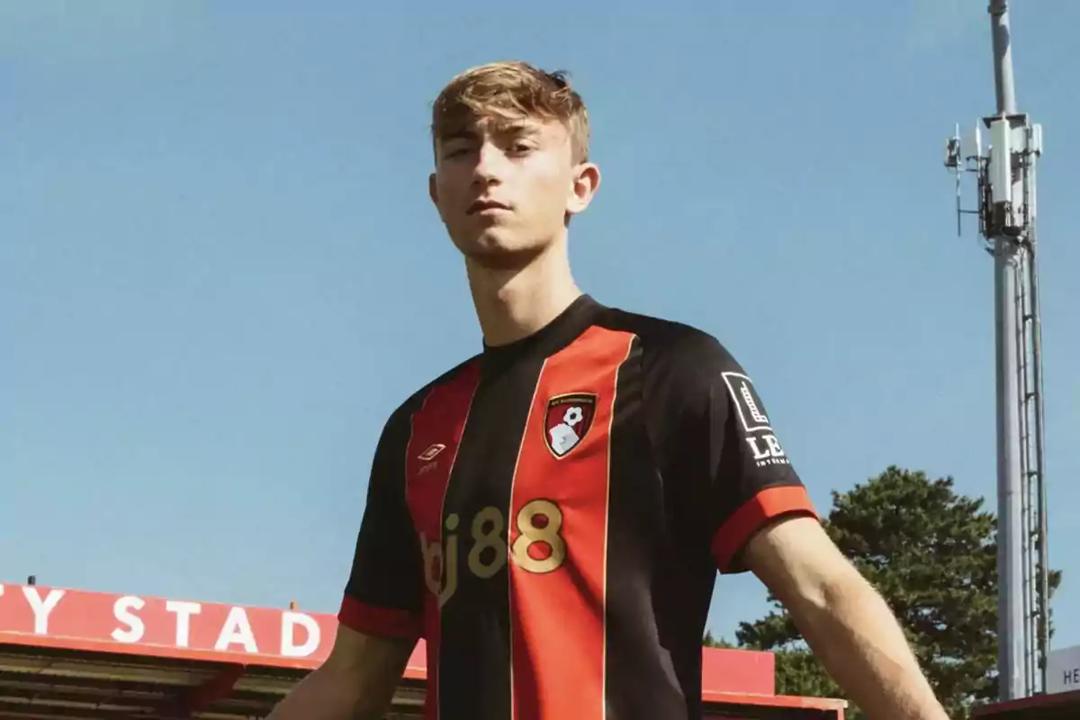 A soccer player in a black and red uniform standing in a stadium under a clear sky. A soccer player in a black and red uniform standing in a stadium under a clear sky.