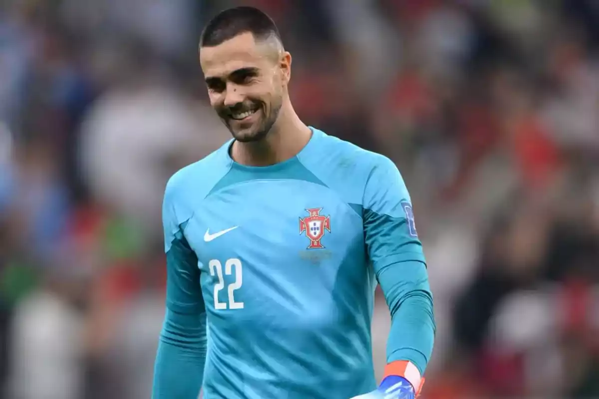 Goalkeeper of the Portugal national soccer team wearing a light blue uniform with the number 22, smiling on the field. Goalkeeper of the Portugal national soccer team wearing a light blue uniform with the number 22, smiling on the field.