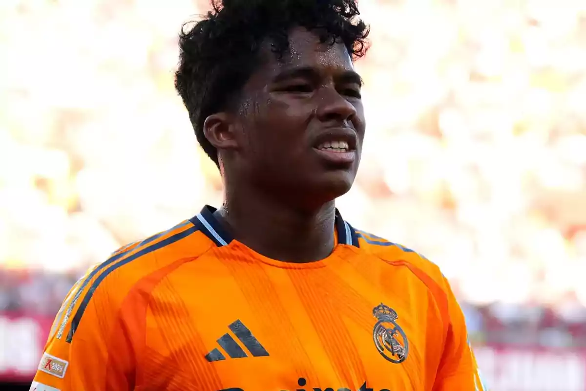A player in an orange Real Madrid jersey on the field. A player in an orange Real Madrid jersey on the field.