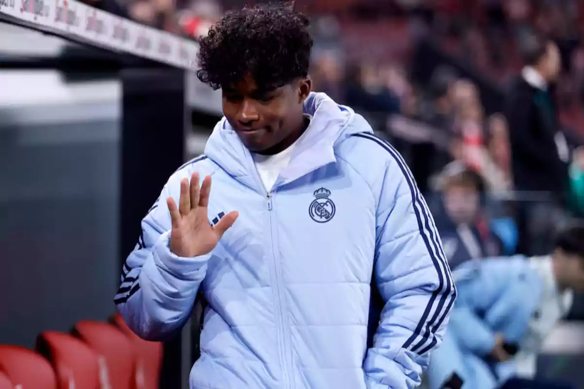 A soccer player wearing a Real Madrid jacket waves at a stadium. A soccer player wearing a Real Madrid jacket waves at a stadium.