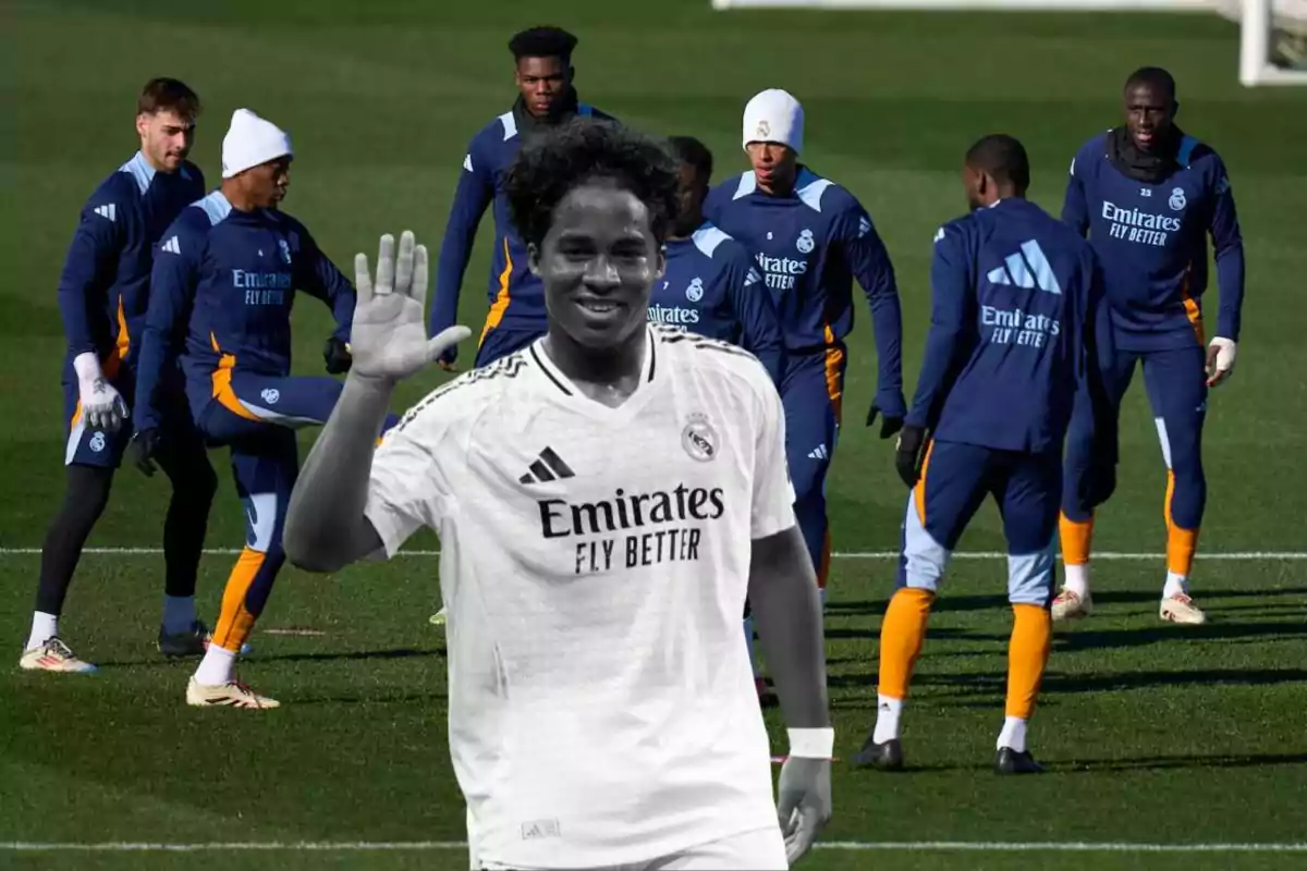 Jugadores de fútbol del Real Madrid entrenando en el campo, con un jugador en primer plano saludando.