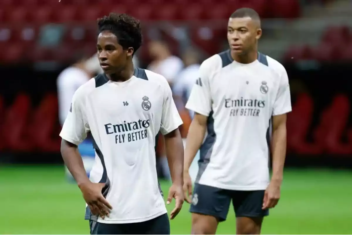 Dos jugadores de fútbol con camisetas de entrenamiento del Real Madrid en un campo de juego. Dos jugadores de fútbol con camisetas de entrenamiento del Real Madrid en un campo de juego.