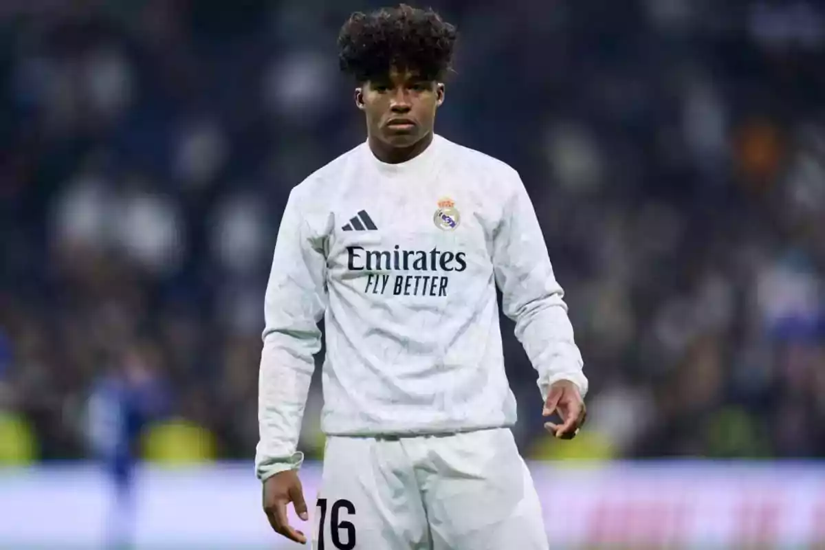 Jugador de fútbol con uniforme blanco del Real Madrid en el campo de juego.