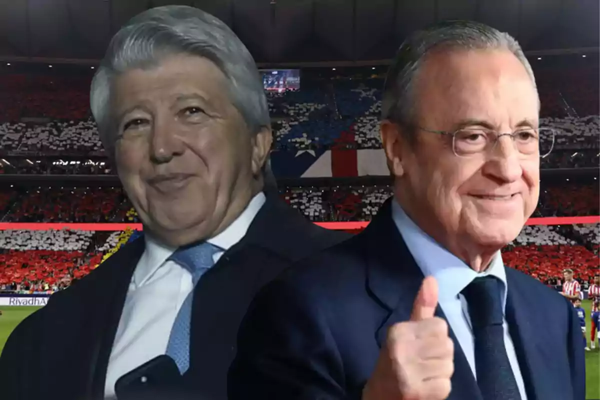 Dos hombres de traje sonríen frente a un estadio lleno de aficionados con banderas y colores en las gradas.