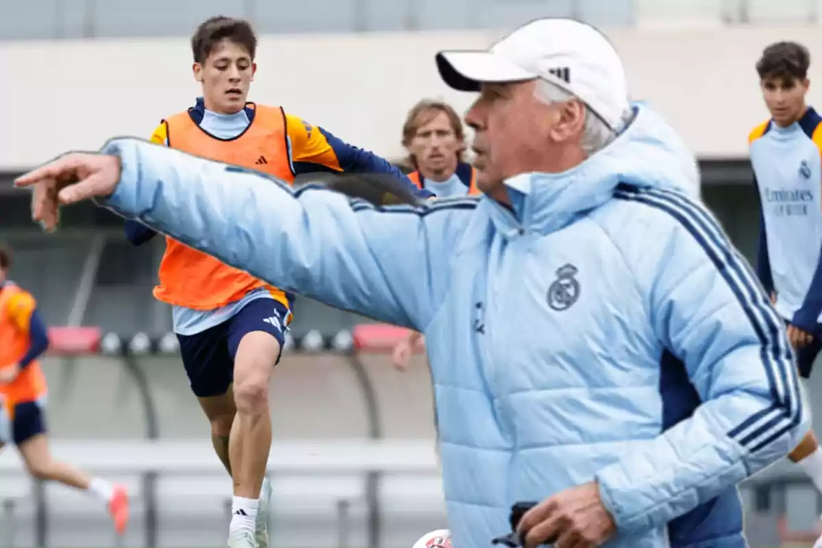 A soccer coach gives instructions as players practice on the field.