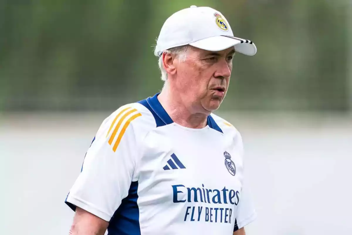 Hombre con gorra y camiseta de entrenamiento del Real Madrid en un campo deportivo.