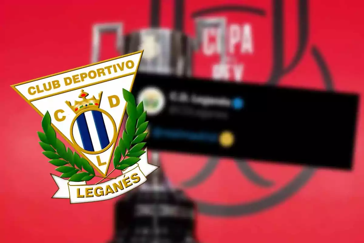 Club Deportivo Leganés shield on a red background with an out-of-focus trophy.