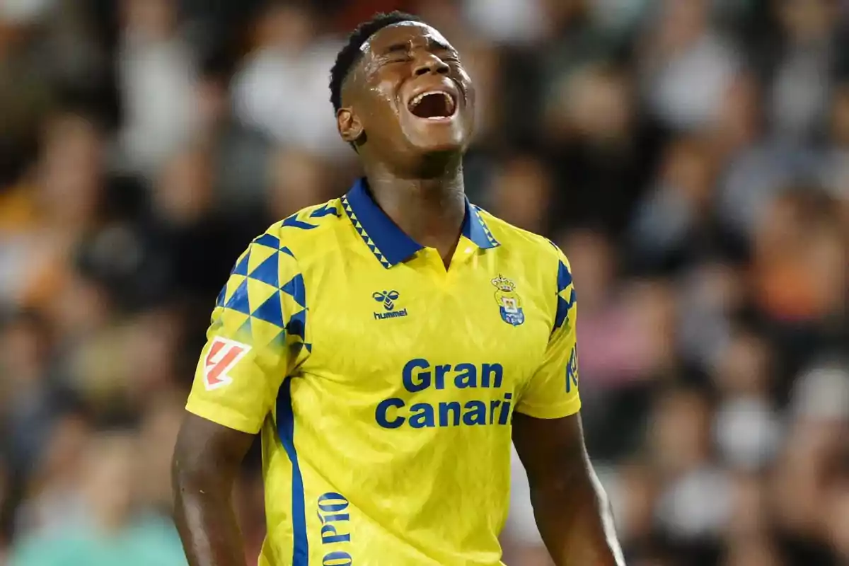 Un jugador de fútbol con uniforme amarillo y azul parece expresar frustración o emoción durante un partido. Un jugador de fútbol con uniforme amarillo y azul parece expresar frustración o emoción durante un partido.