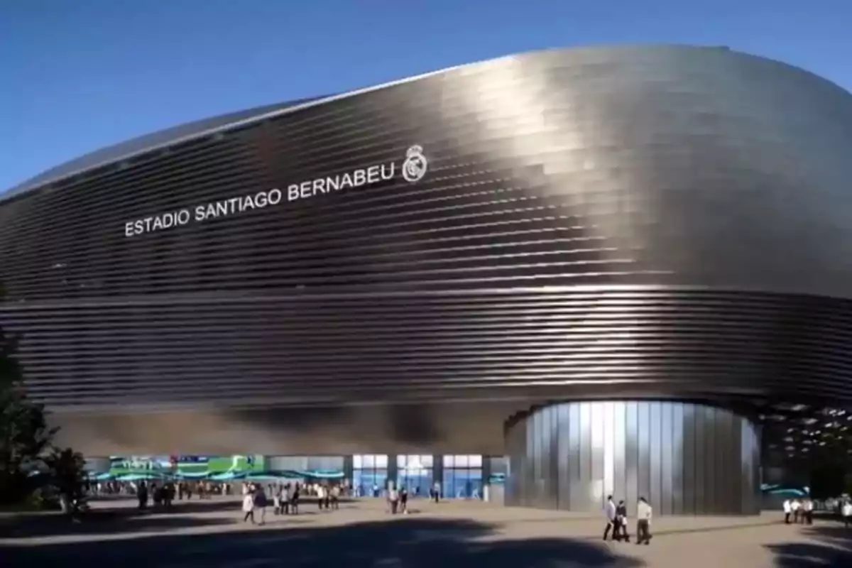 Exterior view of Santiago Bernabéu Stadium with people walking at the entrance.