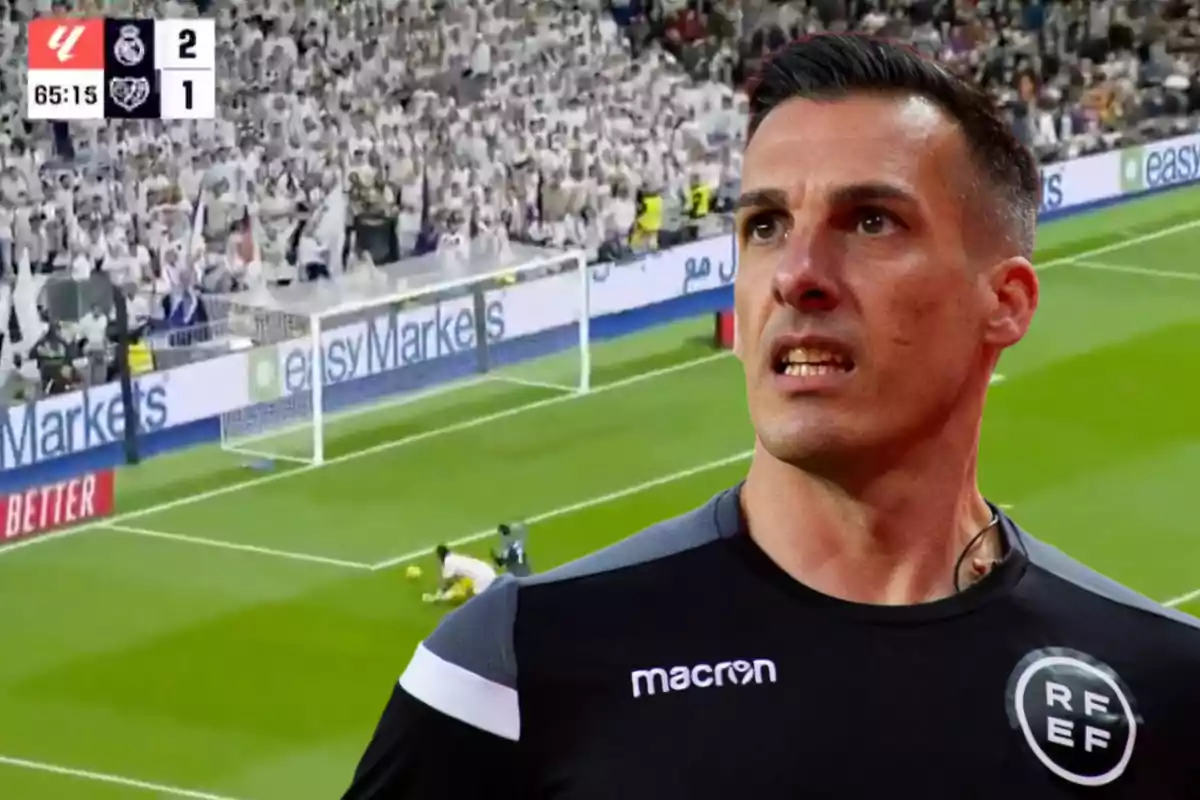 A soccer referee appears in the foreground while a match with a score of 2-1 is seen in the background.