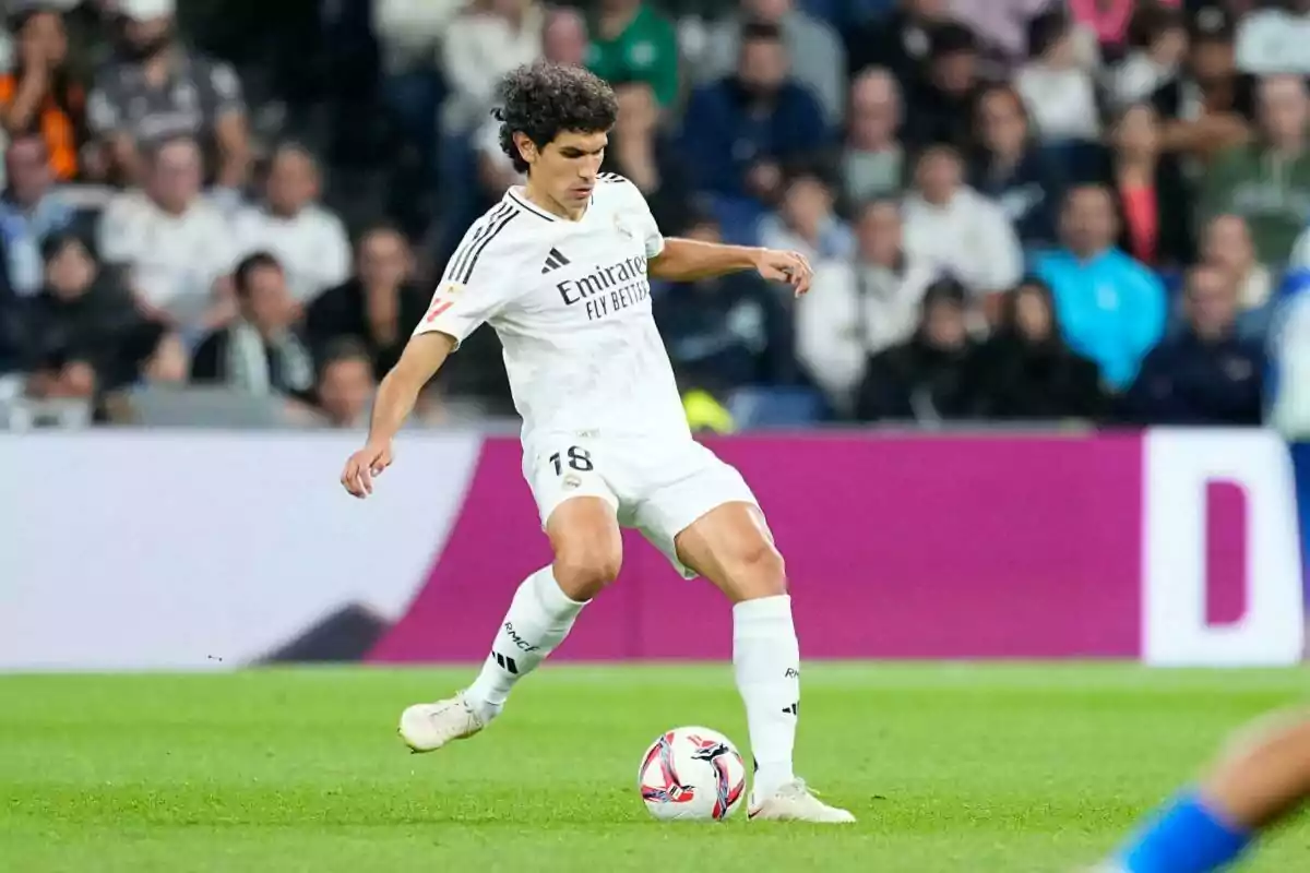 Football player in action during a match, wearing the white uniform of Real Madrid.