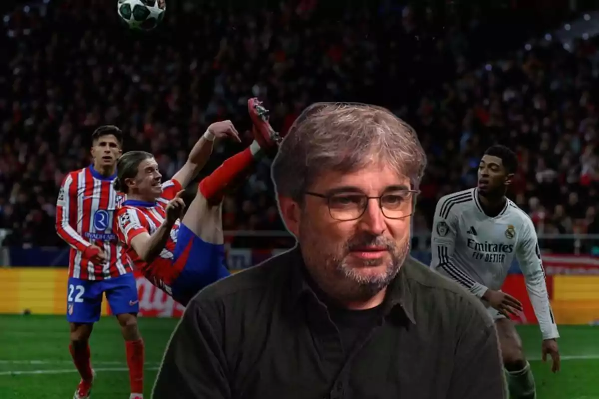 A man with glasses and a beard is in the foreground while a soccer scene unfolds in the background with players from two different teams in action.