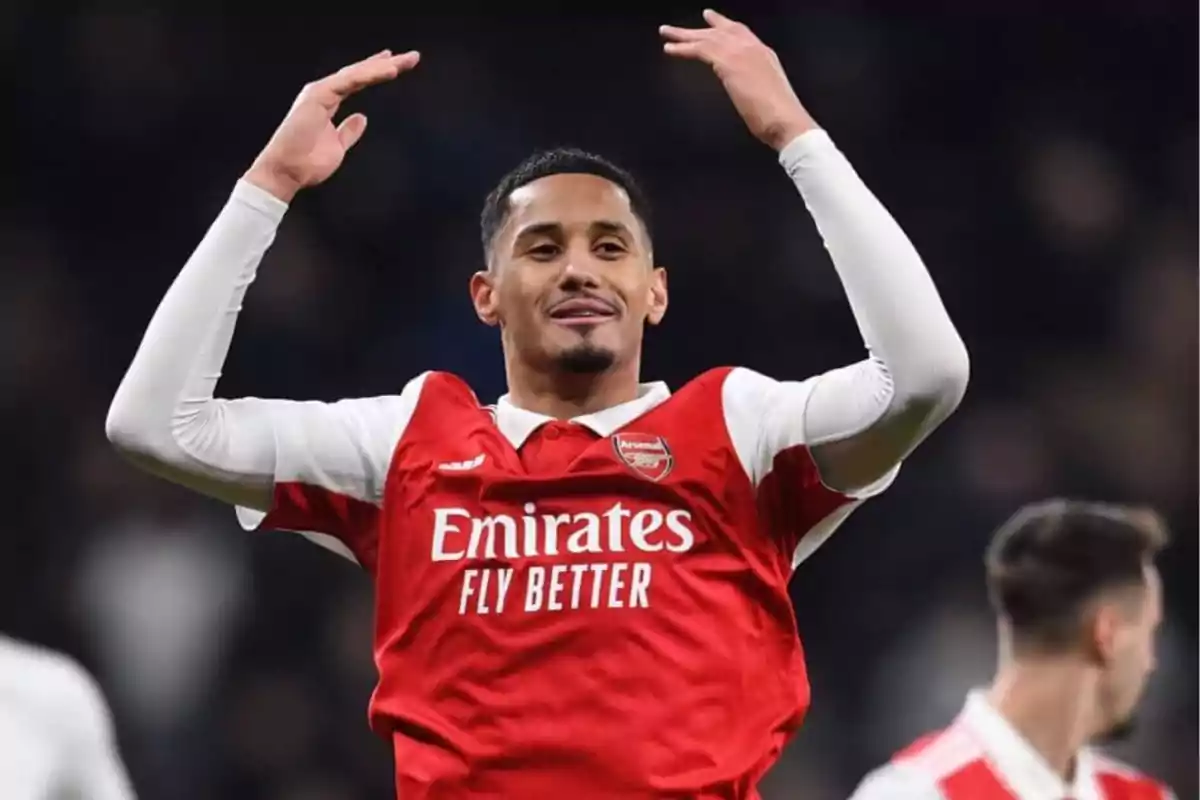 Jugador de fútbol con uniforme rojo y blanco del Arsenal levantando los brazos en celebración durante un partido.