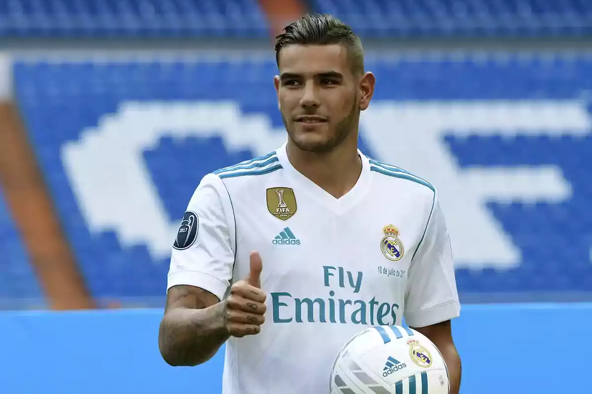 Un jugador de fútbol con el uniforme del Real Madrid sosteniendo un balón y levantando el pulgar en señal de aprobación en un estadio. Un jugador de fútbol con el uniforme del Real Madrid sosteniendo un balón y levantando el pulgar en señal de aprobación en un estadio.