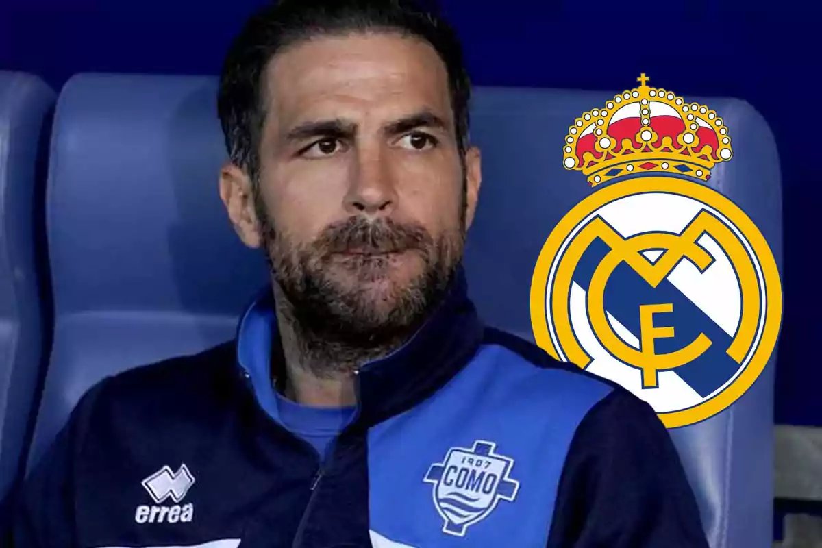 Un hombre con chaqueta deportiva azul y el escudo del Real Madrid al fondo.