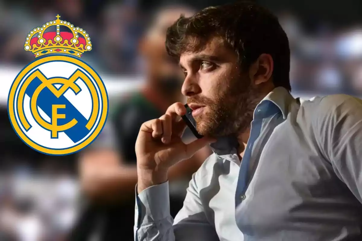 Un hombre hablando por teléfono con el logo del Real Madrid al fondo.