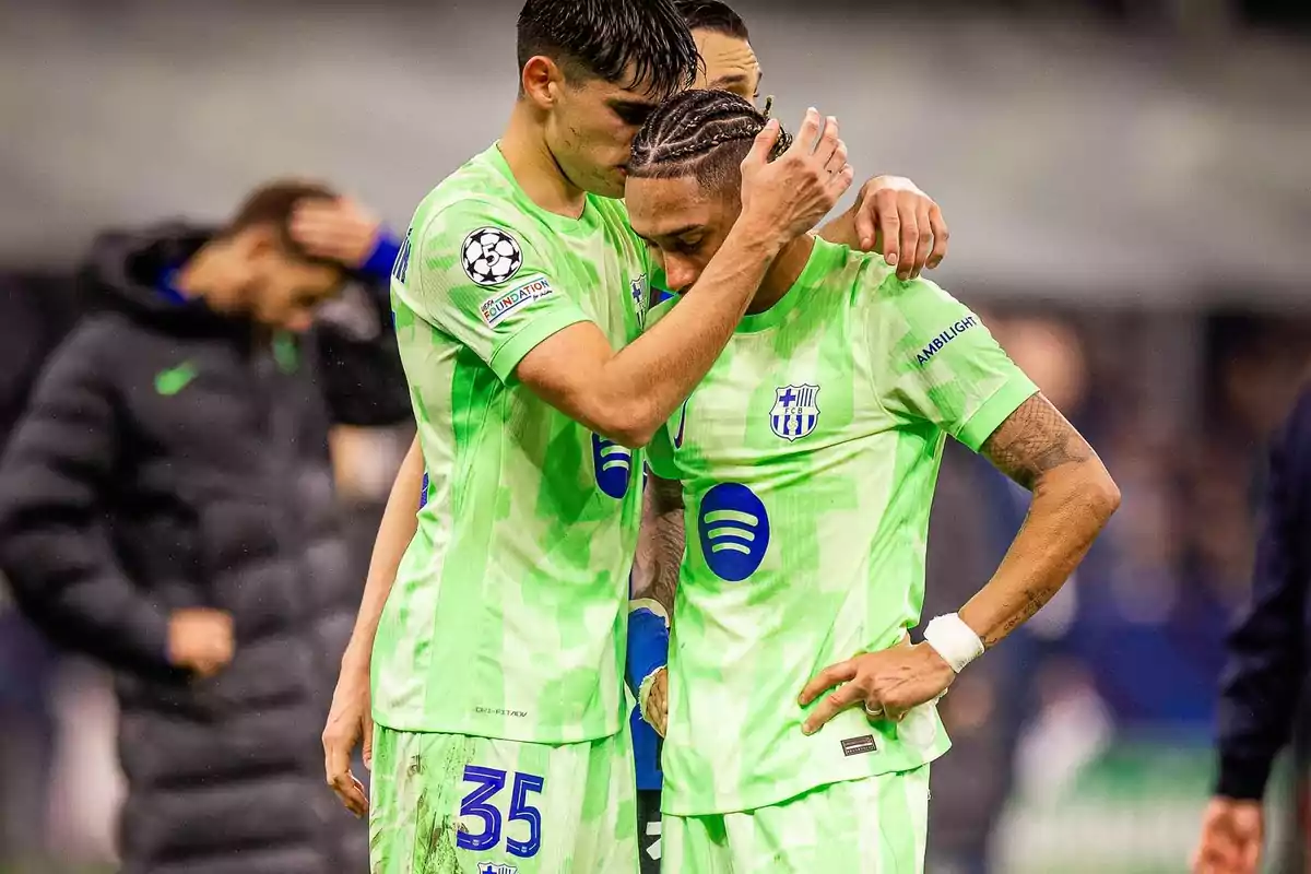 Two players in green uniforms comfort each other on the field after a match. Two players in green uniforms comfort each other on the field after a match.
