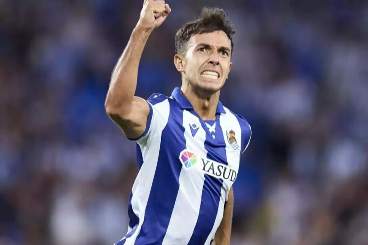 Soccer player celebrating with his fist raised while wearing a blue and white striped uniform.