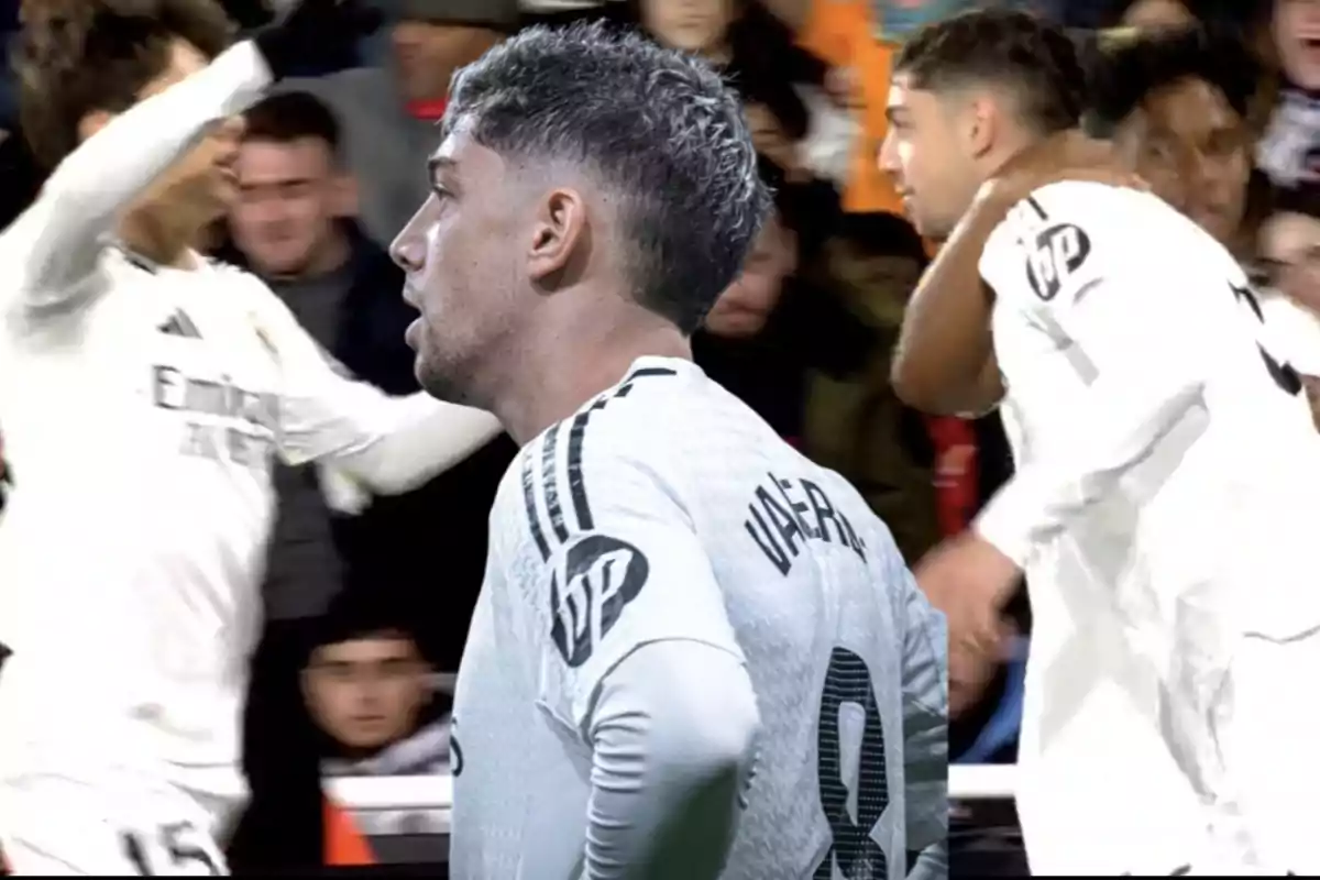 Jugadores de fútbol celebrando en el campo con camisetas blancas.