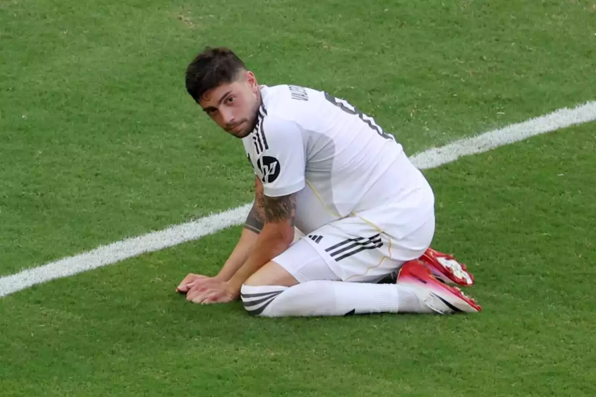 Futbolista de uniforme blanco arrodillado sobre el césped mirando hacia la cámara Futbolista de uniforme blanco arrodillado sobre el césped mirando hacia la cámara