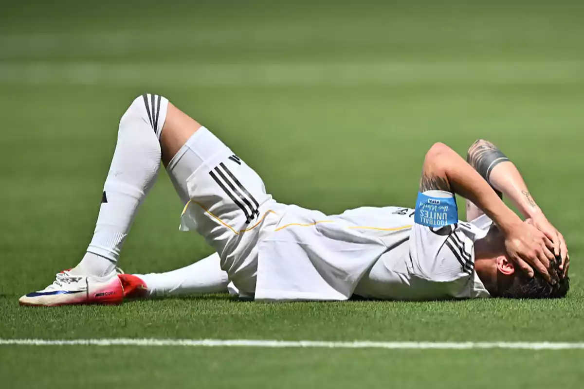 Futbolista acostado en el césped con las manos en la cabeza mostrando frustración durante un partido Futbolista acostado en el césped con las manos en la cabeza mostrando frustración durante un partido