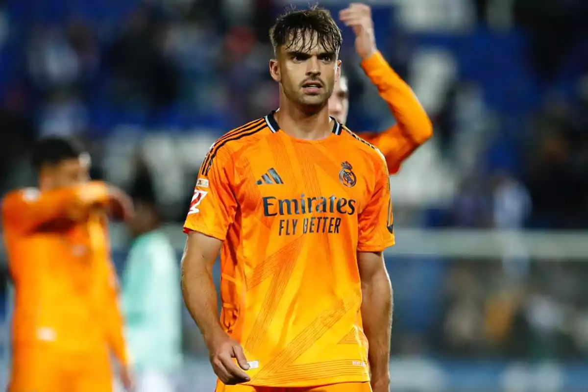 Soccer player in orange Real Madrid uniform on the field.