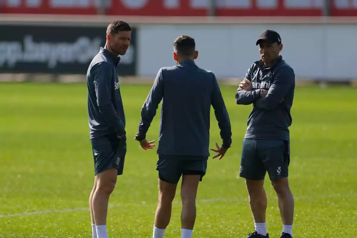 Tres personas conversando en un campo de entrenamiento de fútbol. Tres personas conversando en un campo de entrenamiento de fútbol.