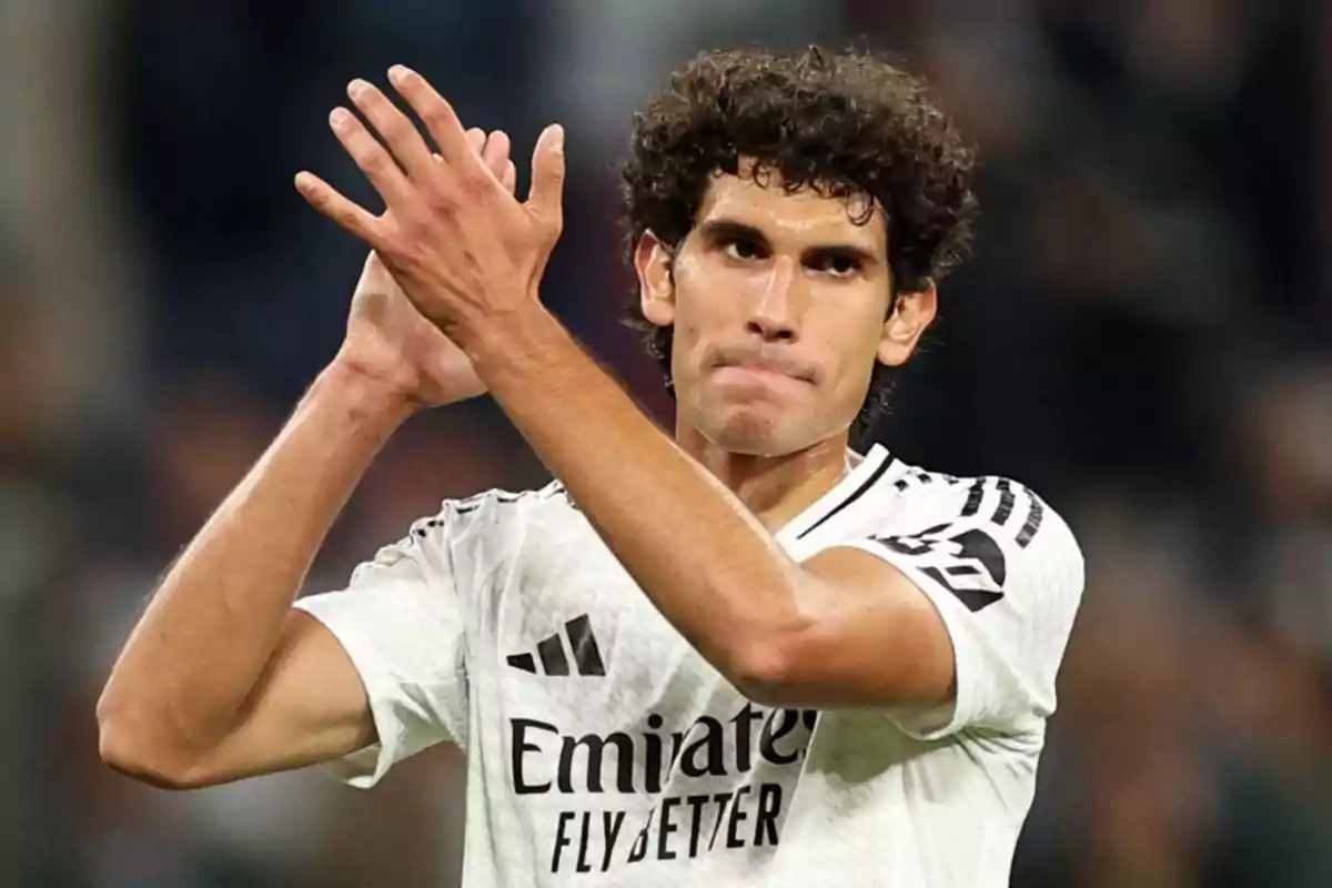 Football player applauding on the field in white uniform.