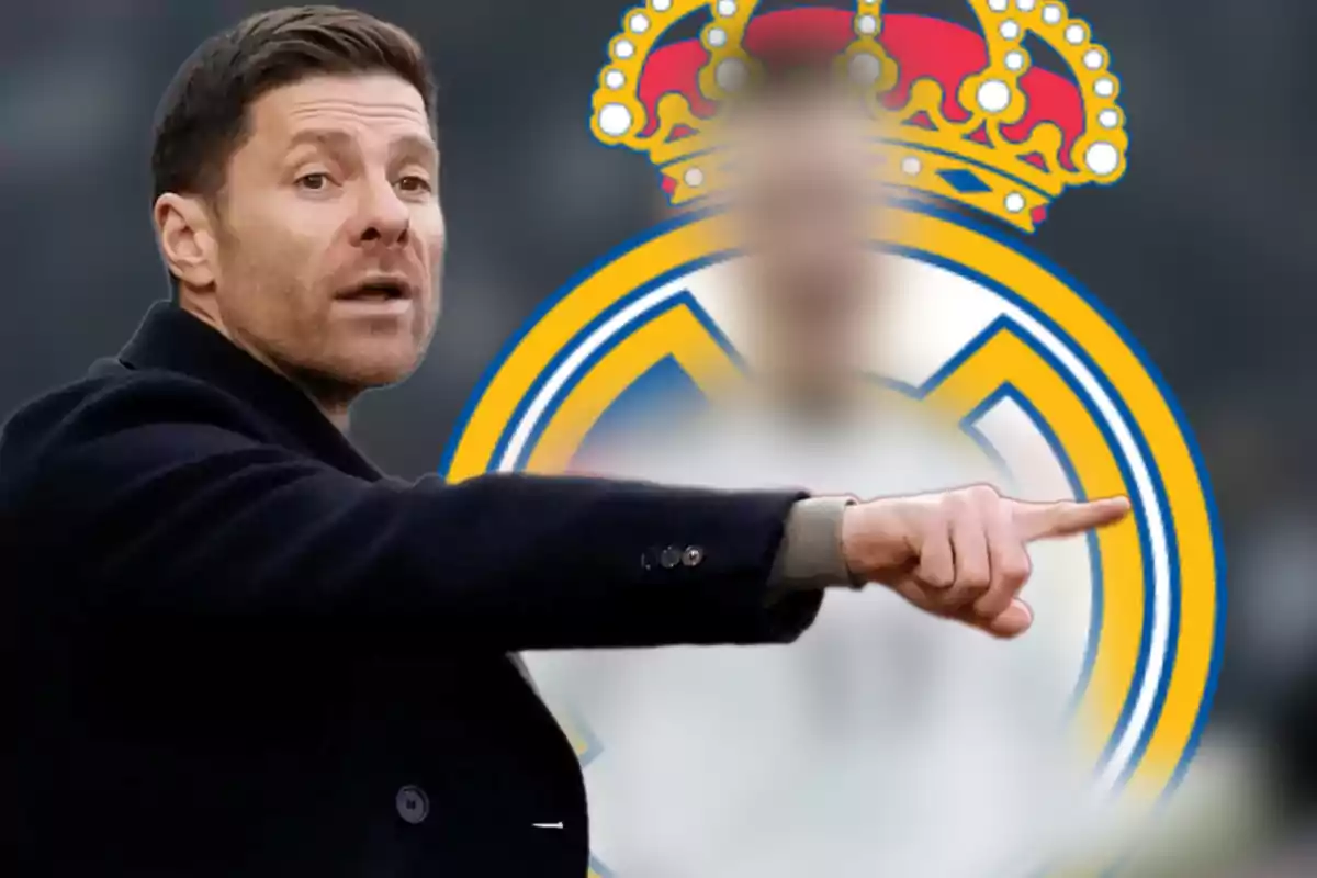 A man pointing with his finger in front of a blurred soccer team shield.