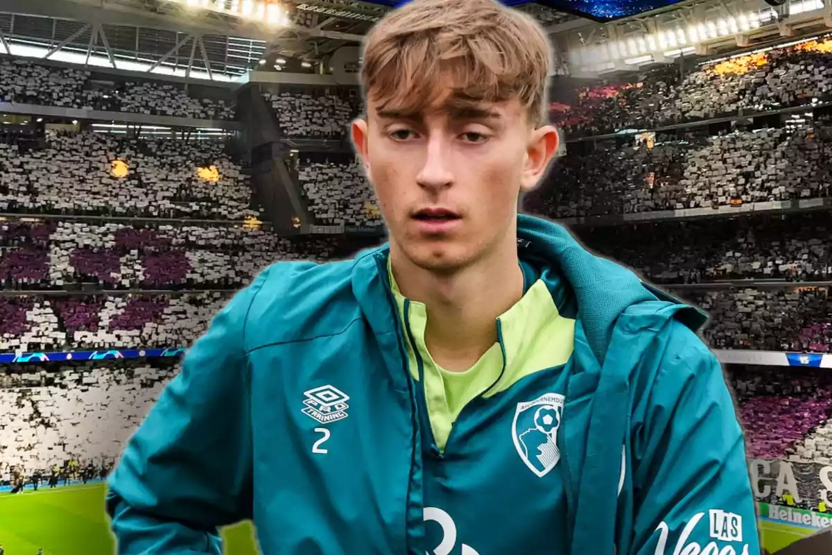 Un jugador de fútbol con chaqueta verde y logo de Umbro en un estadio lleno de espectadores.