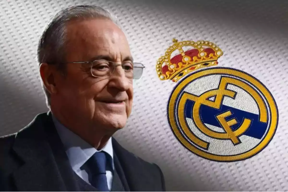 Hombre de cabello canoso y gafas sonríe con el escudo del Real Madrid al fondo sobre una camiseta blanca