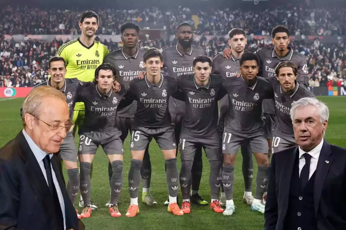 A soccer team posing on the field with two people in suits in the foreground.