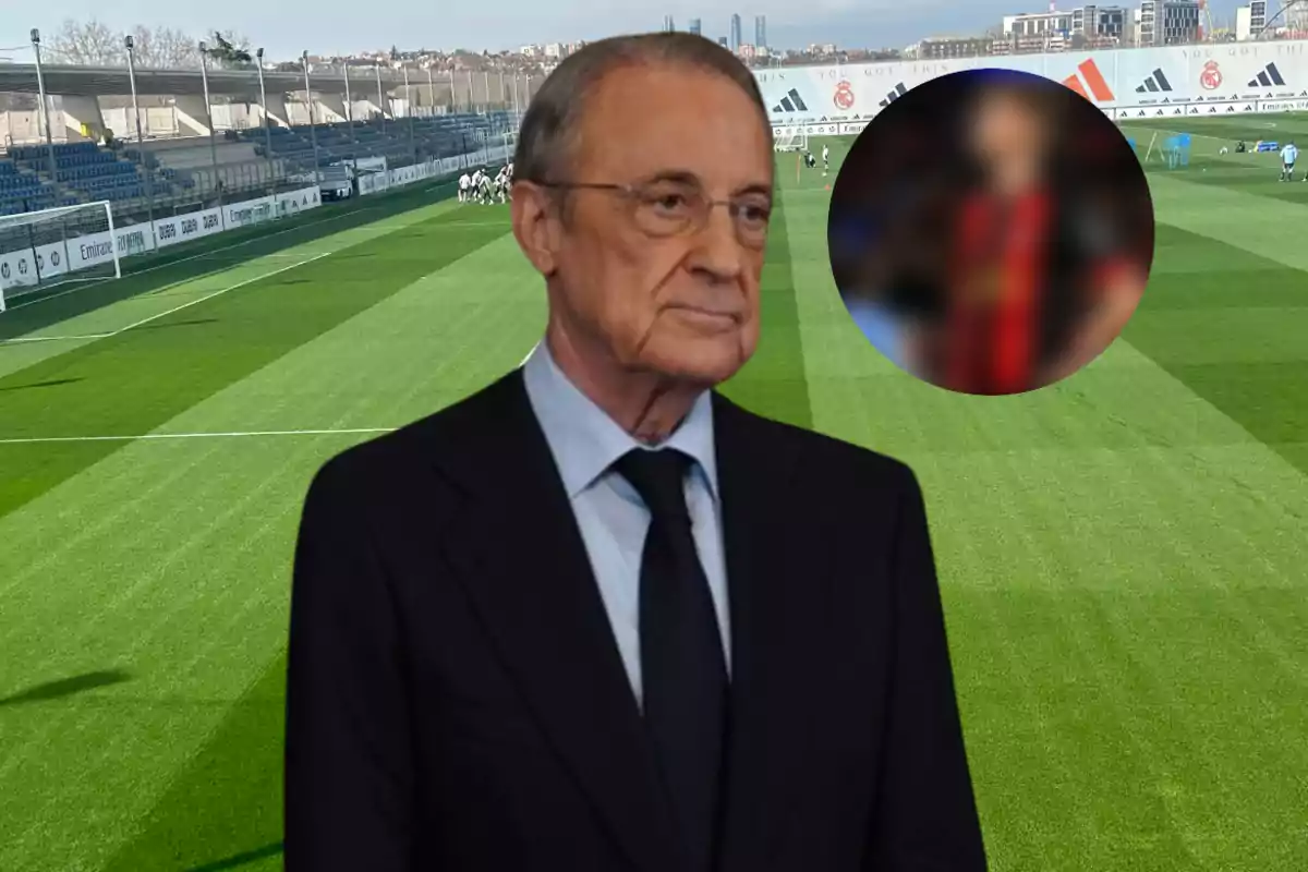 A man in a suit and tie is standing on a soccer field, with stands and a city in the background.