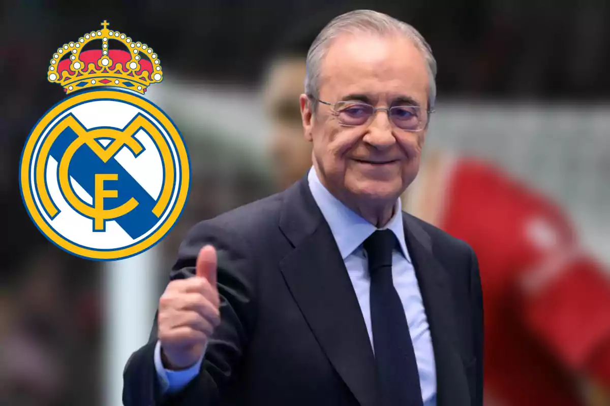 Un hombre con traje sonríe y levanta el pulgar junto al escudo del Real Madrid.