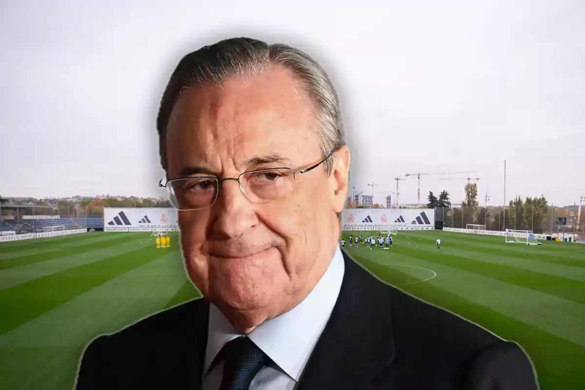 Older man with glasses and a suit in front of a soccer training field