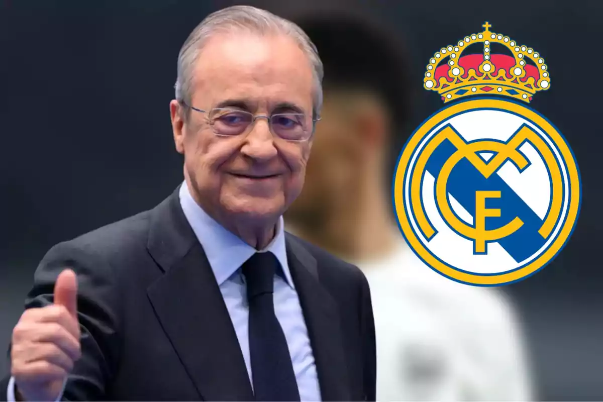 Un hombre con gafas y traje sonríe mientras hace un gesto de aprobación con el pulgar levantado, junto al escudo del Real Madrid.