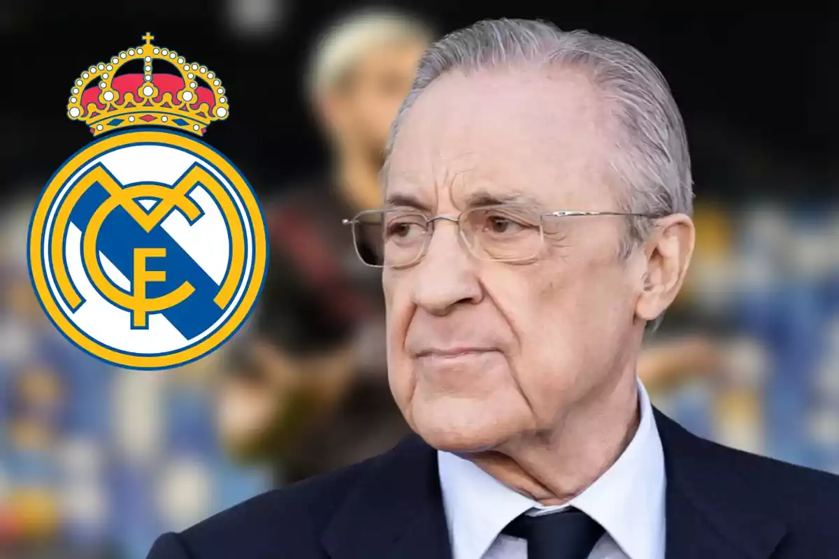 An older man with glasses and a dark suit is standing next to the Real Madrid crest.