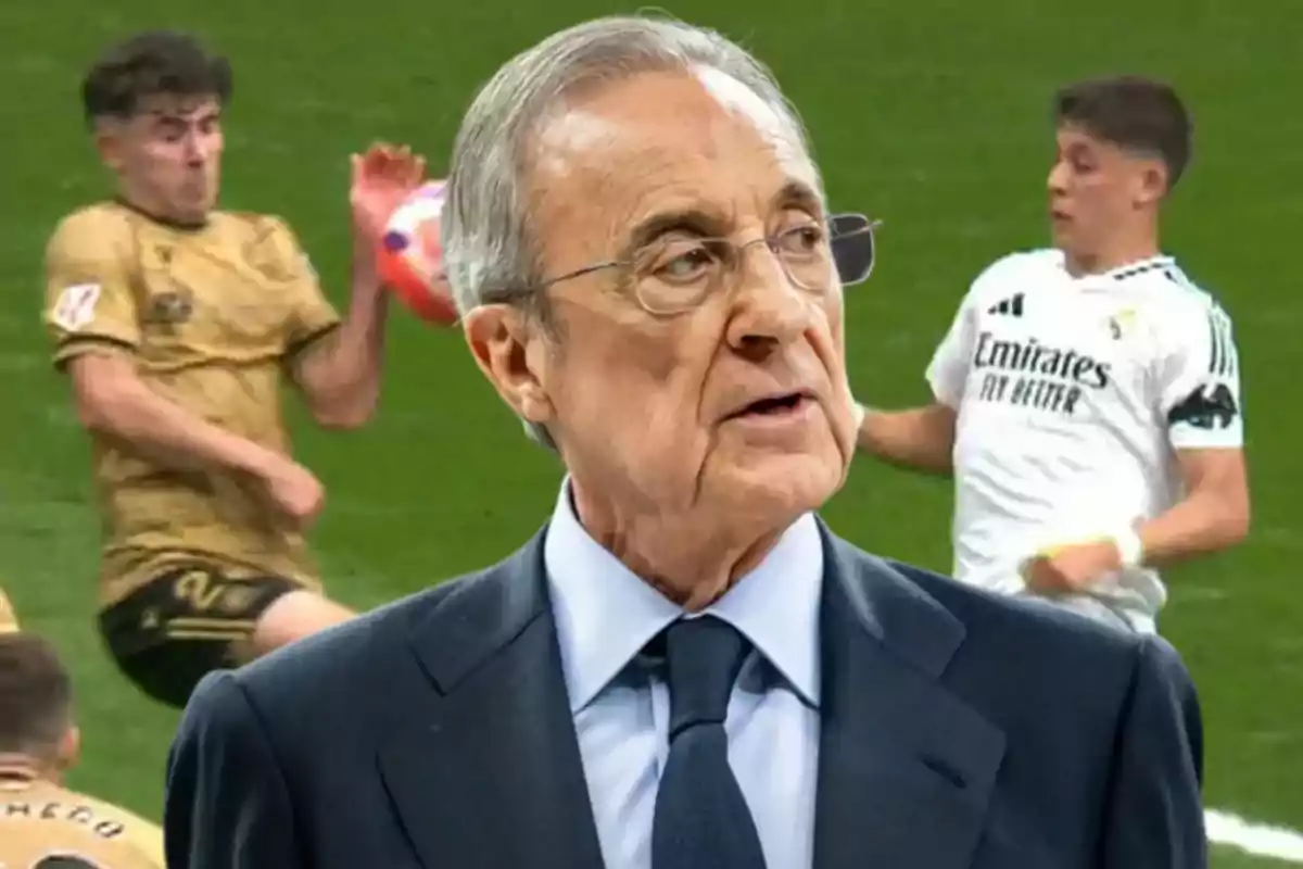 Un hombre mayor con gafas y traje oscuro aparece en primer plano mientras dos jugadores de fútbol en acción se ven de fondo en un campo de juego.