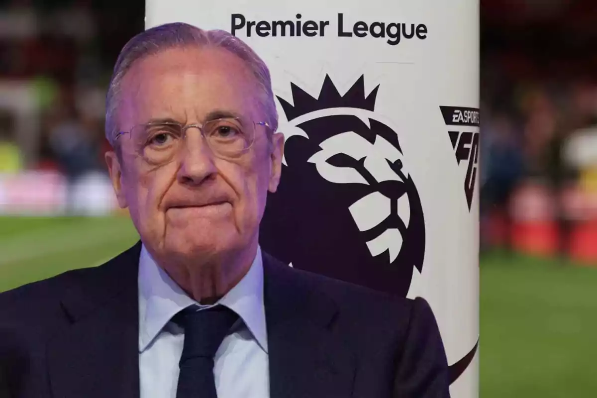A man in a suit and tie is standing in front of a Premier League sign.