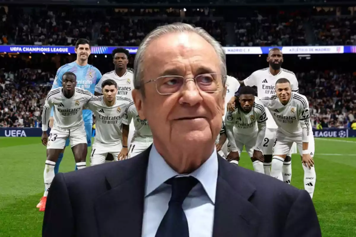 Un hombre mayor con gafas y traje está en primer plano, mientras que detrás de él hay un grupo de jugadores de fútbol en uniforme blanco posando en un estadio lleno de espectadores.